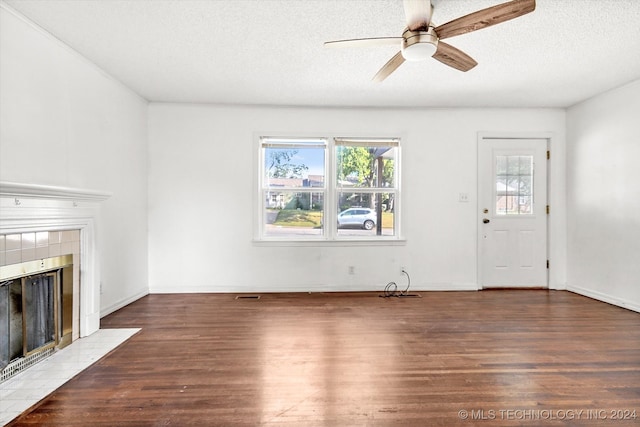 unfurnished living room featuring dark wood-type flooring, ceiling fan, a fireplace, and a textured ceiling