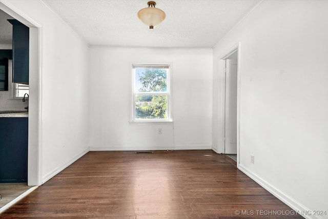 unfurnished room featuring dark hardwood / wood-style floors, ornamental molding, and a textured ceiling