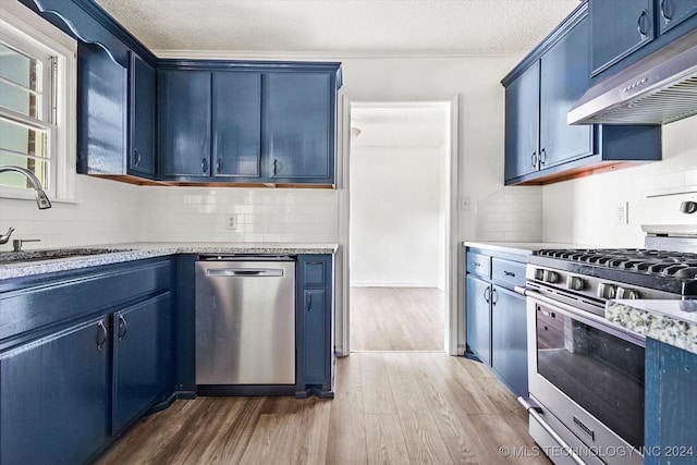 kitchen with range hood, blue cabinetry, hardwood / wood-style floors, appliances with stainless steel finishes, and decorative backsplash