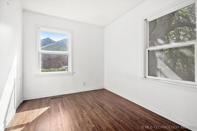 spare room with ornamental molding, dark hardwood / wood-style floors, and a textured ceiling