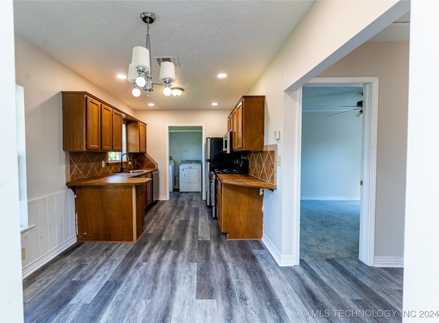 kitchen featuring washer and clothes dryer, ceiling fan with notable chandelier, tasteful backsplash, sink, and dark wood-type flooring