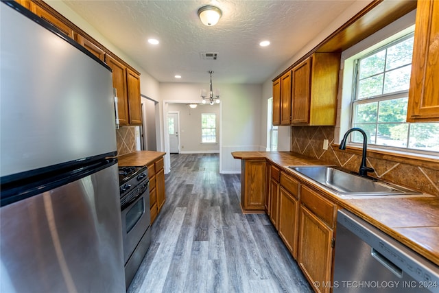 kitchen with pendant lighting, sink, appliances with stainless steel finishes, and light hardwood / wood-style floors