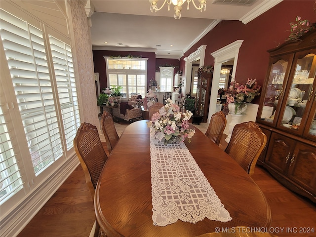 dining area with crown molding, plenty of natural light, hardwood / wood-style floors, and a chandelier