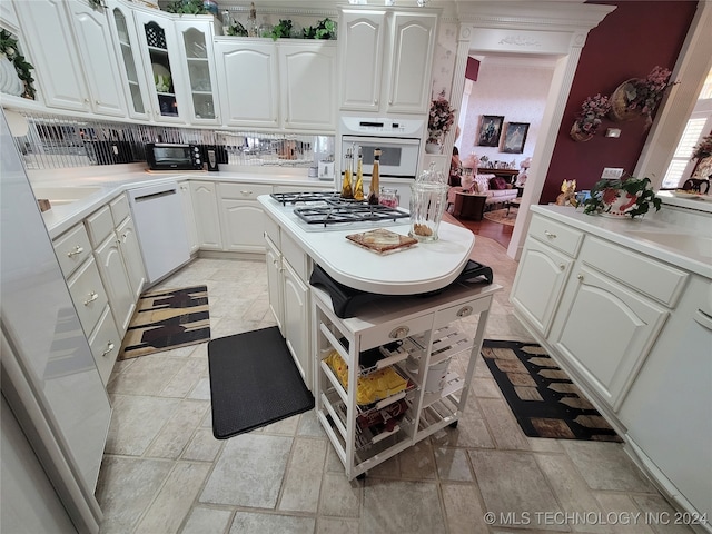 kitchen featuring white appliances, backsplash, and white cabinetry