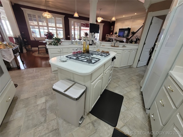 kitchen featuring pendant lighting, crown molding, a kitchen island, kitchen peninsula, and white cabinets