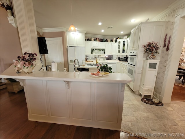 kitchen with white refrigerator with ice dispenser, crown molding, a spacious island, hanging light fixtures, and light hardwood / wood-style floors