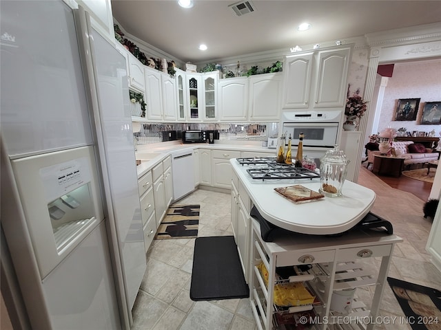 kitchen with light tile patterned floors, white appliances, tasteful backsplash, and white cabinetry