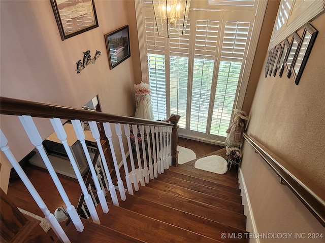 staircase featuring wood-type flooring and a chandelier