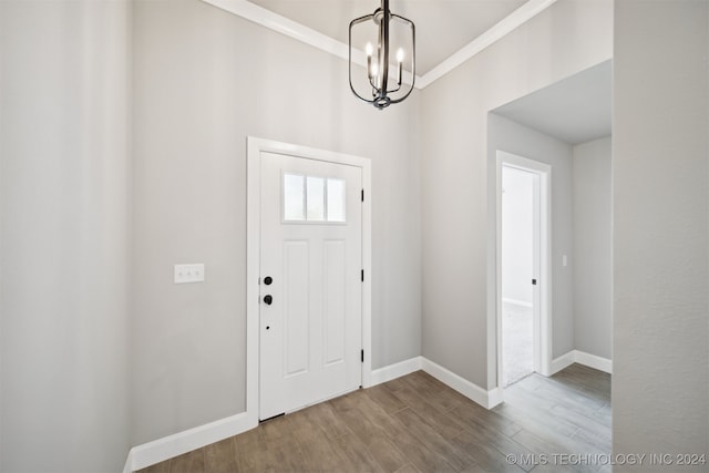 foyer featuring crown molding, hardwood / wood-style flooring, and a chandelier