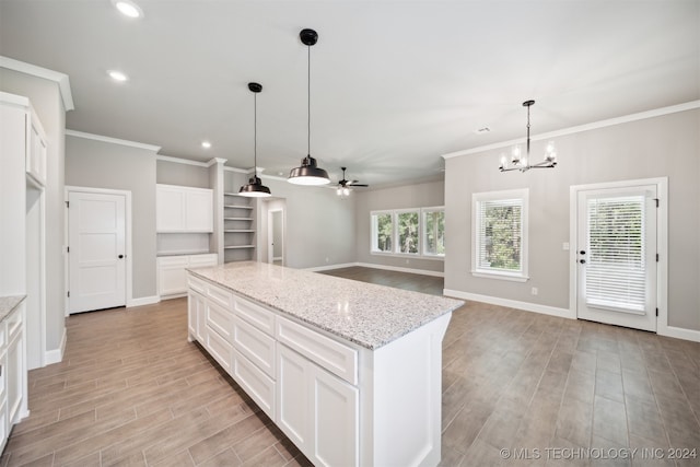 kitchen with ceiling fan with notable chandelier, light stone countertops, light hardwood / wood-style flooring, a center island, and white cabinetry