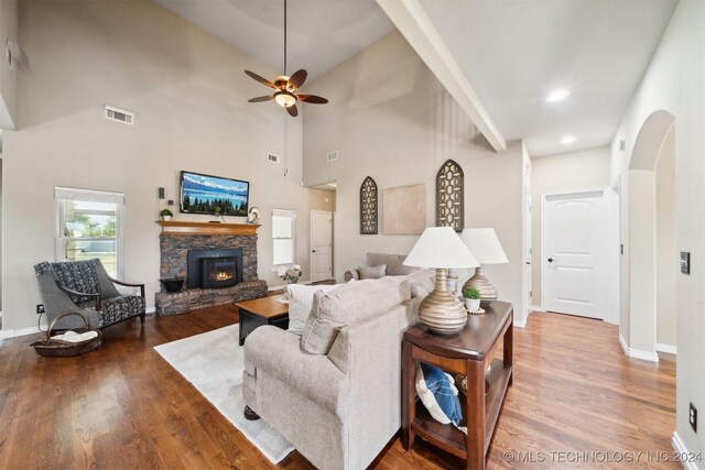 living room featuring ceiling fan, a fireplace, a high ceiling, and hardwood / wood-style flooring