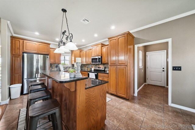 kitchen with appliances with stainless steel finishes, a center island, ornamental molding, and backsplash