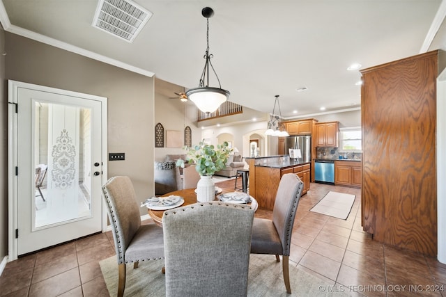 tiled dining space featuring crown molding, sink, and ceiling fan