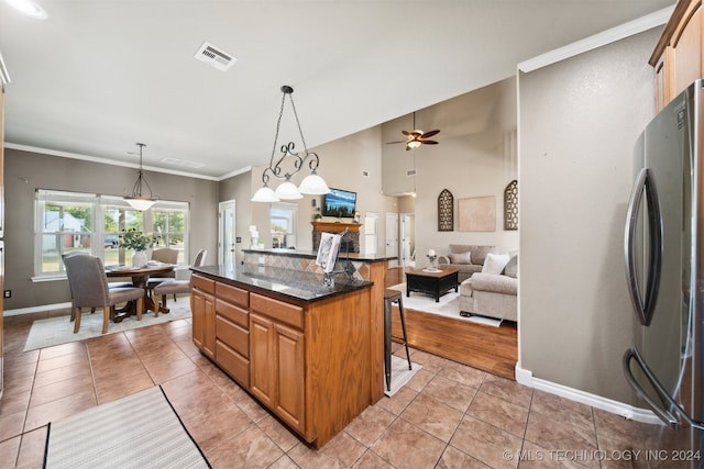 kitchen featuring pendant lighting, a kitchen breakfast bar, ornamental molding, a kitchen island, and stainless steel refrigerator