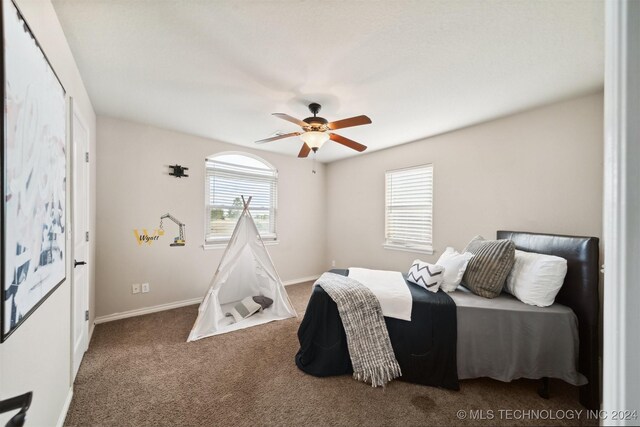 carpeted bedroom with multiple windows and ceiling fan