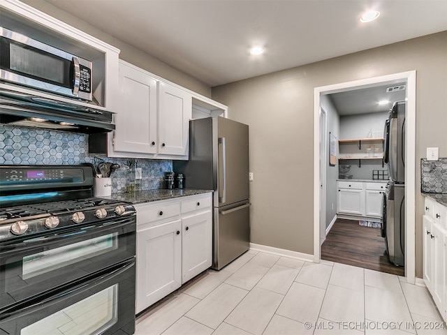 kitchen featuring appliances with stainless steel finishes, decorative backsplash, dark stone counters, and white cabinetry