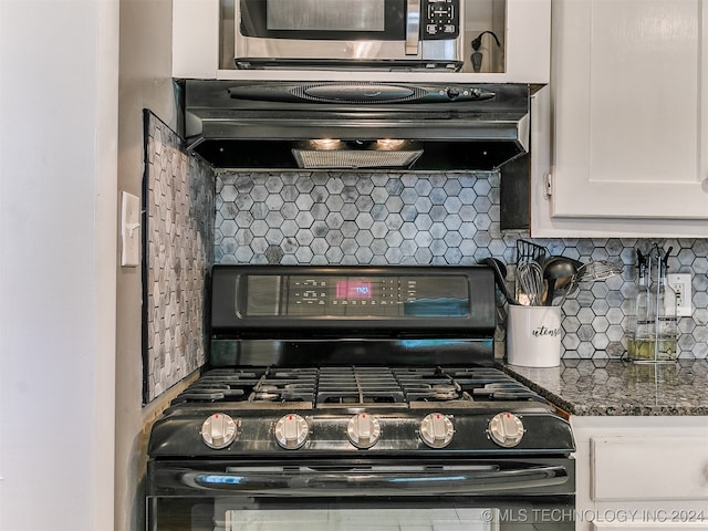 interior space with ventilation hood, white cabinets, dark stone countertops, black range with gas stovetop, and decorative backsplash