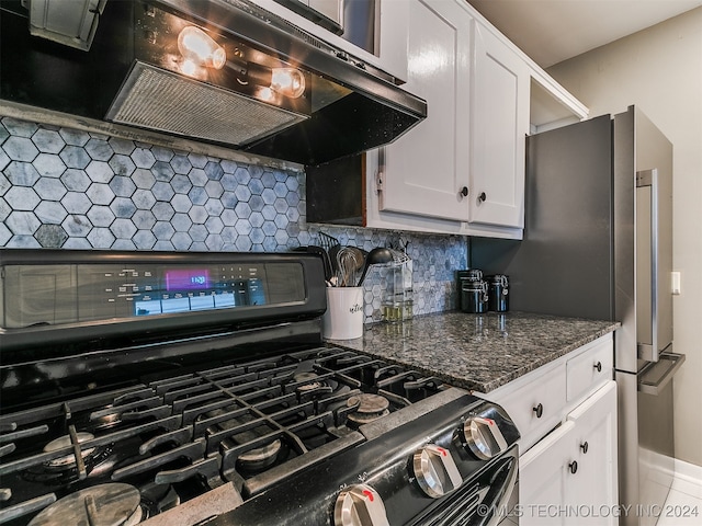 kitchen featuring dark stone countertops, white cabinets, stainless steel gas range oven, decorative backsplash, and extractor fan