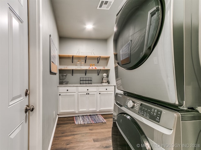 laundry room with dark hardwood / wood-style flooring and stacked washer / dryer