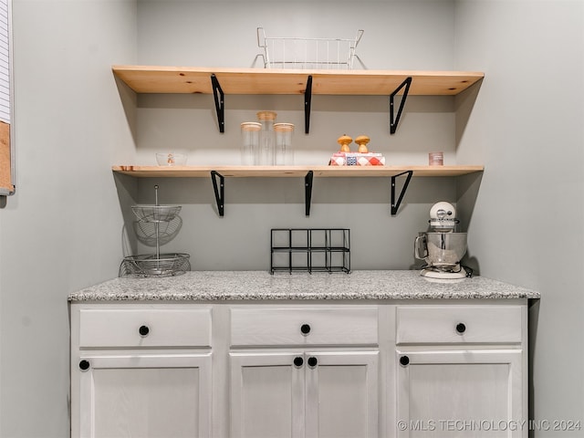 interior space with light stone countertops and white cabinets