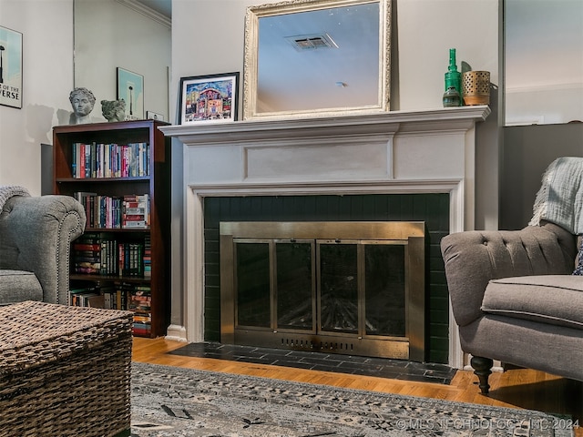 living room with hardwood / wood-style flooring, a tiled fireplace, and crown molding