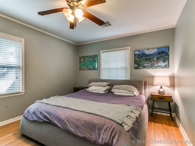 bedroom with crown molding, light hardwood / wood-style flooring, ceiling fan, and multiple windows