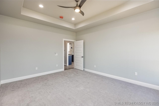 spare room with light carpet, ceiling fan, and a tray ceiling