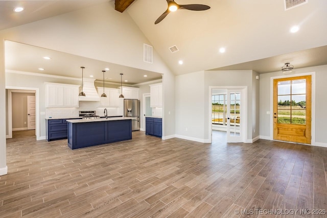 kitchen featuring white cabinetry, blue cabinetry, pendant lighting, and premium range hood