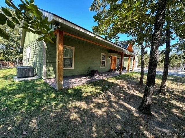 view of side of property with a lawn, a patio area, and cooling unit