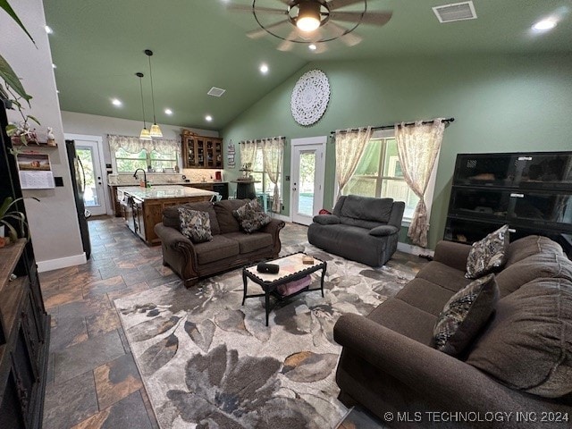 living room with a healthy amount of sunlight, ceiling fan, sink, and high vaulted ceiling