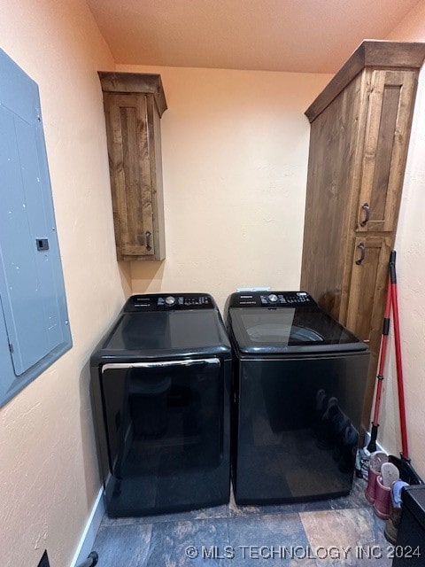 laundry area featuring electric panel, washing machine and clothes dryer, and cabinets