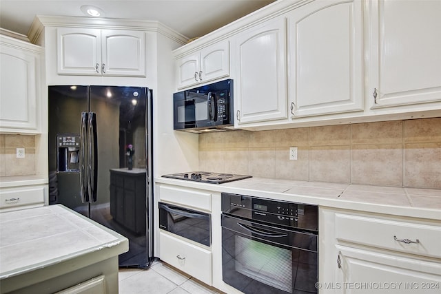 2116 E 59th Pl Unit 4F, Tulsa, OK 74105 - kitchen with black appliances, white cabinetry, backsplash, tile counters, and light tile patterned flooring