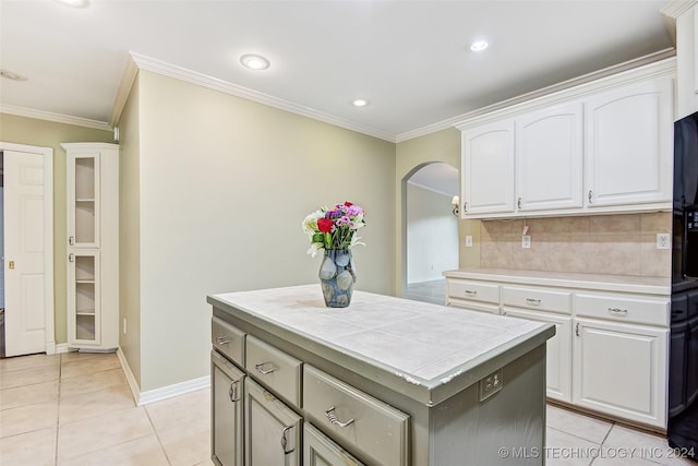 2116 E 59th Pl Unit 4F, Tulsa, OK 74105 - kitchen featuring tile counters, ornamental molding, arched walkways, white cabinets, and light tile patterned floors