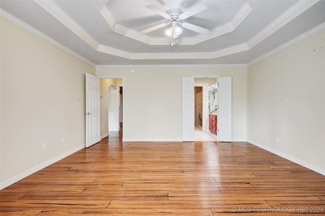 2116 E 59th Pl Unit 4F, Tulsa, OK 74105 - spare room featuring a raised ceiling, light wood finished floors, a ceiling fan, crown molding, and arched walkways