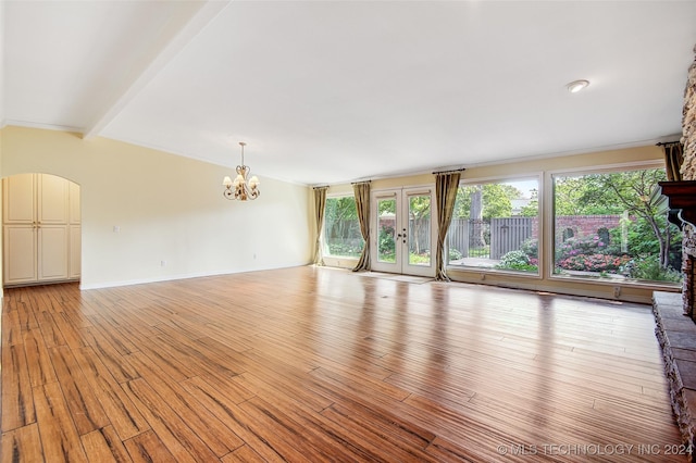 2116 E 59th Pl Unit 4F, Tulsa, OK 74105 - unfurnished living room featuring plenty of natural light, a chandelier, light wood finished floors, beam ceiling, and french doors