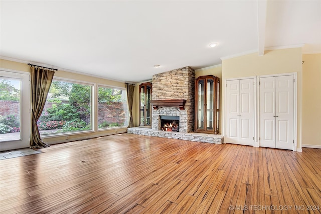 2116 E 59th Pl Unit 4F, Tulsa, OK 74105 - unfurnished living room with plenty of natural light, light wood-type flooring, ornamental molding, and a stone fireplace