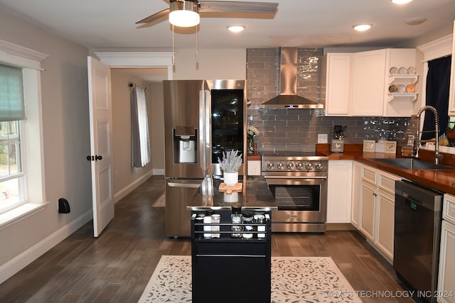 kitchen with stainless steel appliances, sink, wall chimney range hood, and white cabinetry