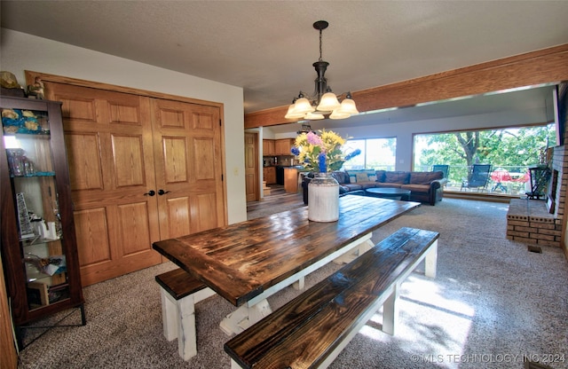 carpeted dining room with a textured ceiling and an inviting chandelier