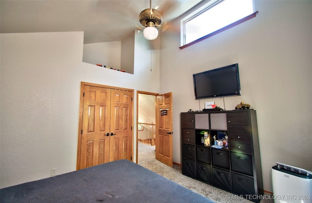 bedroom featuring a towering ceiling, light colored carpet, and ceiling fan