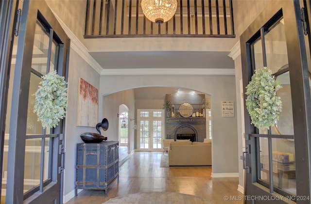 foyer entrance featuring hardwood / wood-style floors, a fireplace, a chandelier, and ornamental molding