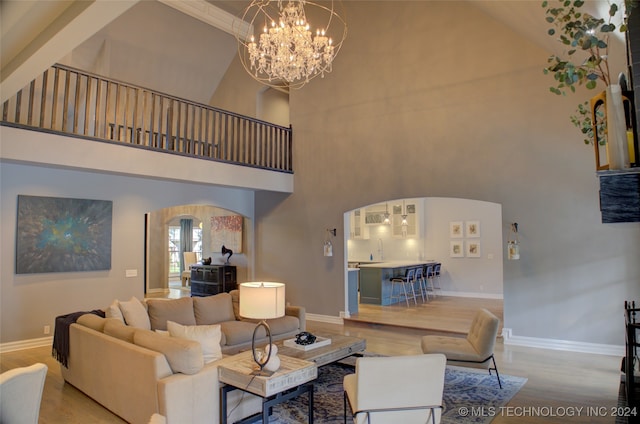 living room featuring high vaulted ceiling, light hardwood / wood-style flooring, and an inviting chandelier