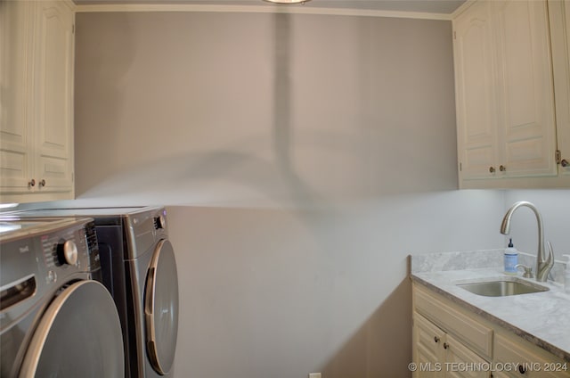 clothes washing area featuring crown molding, cabinets, washing machine and dryer, and sink