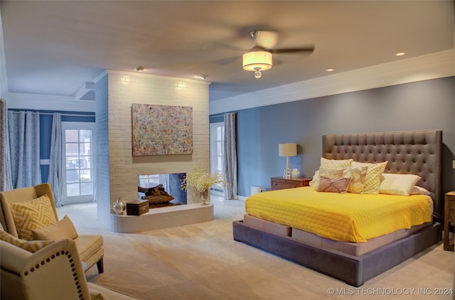 carpeted bedroom featuring ceiling fan, access to exterior, crown molding, and a brick fireplace