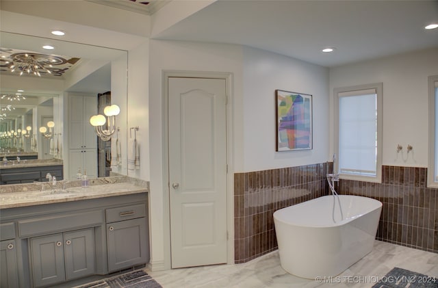 bathroom with crown molding, vanity, a bath, and tile walls