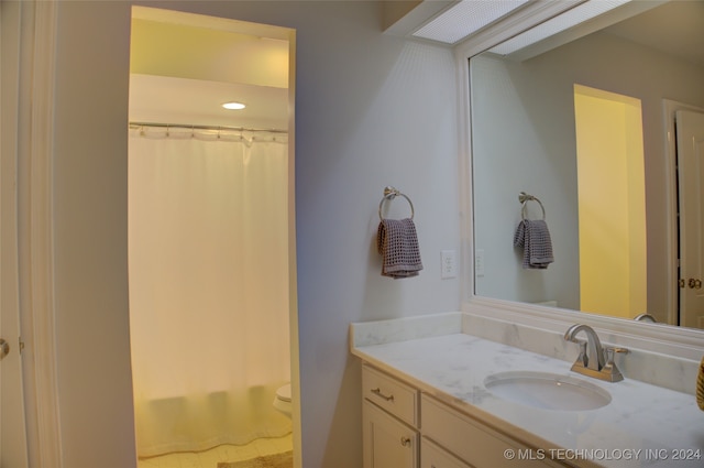 bathroom featuring vanity, toilet, and curtained shower