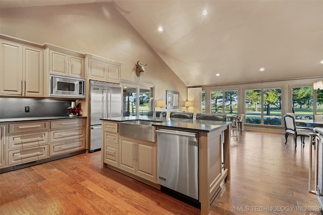 kitchen with built in appliances, sink, high vaulted ceiling, and light hardwood / wood-style floors