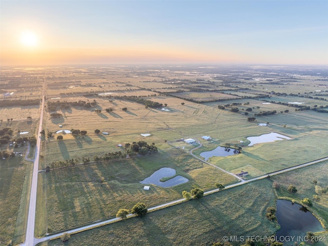 aerial view at dusk with a water view and a rural view