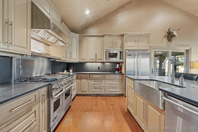 kitchen featuring backsplash, light hardwood / wood-style flooring, cream cabinetry, built in appliances, and exhaust hood