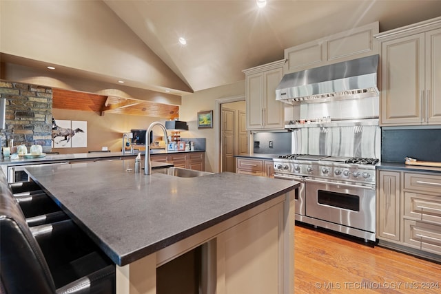 kitchen featuring a kitchen breakfast bar, an island with sink, sink, ventilation hood, and high end range