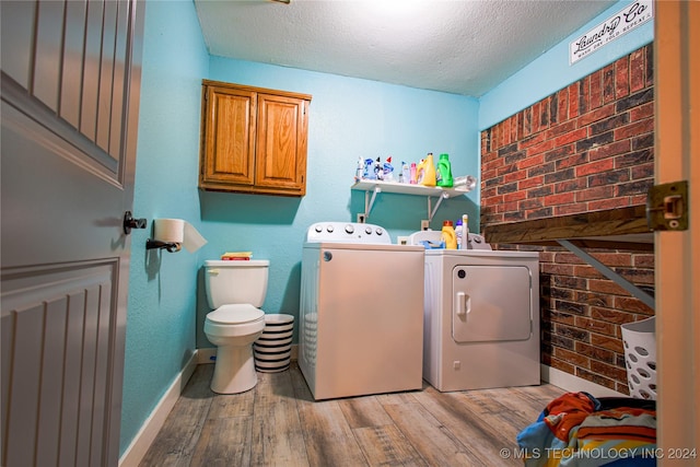 laundry area featuring light wood-type flooring, separate washer and dryer, and a textured ceiling